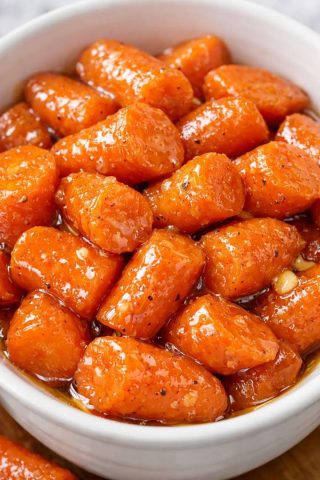 Ferdiglagde honningglaserte gulrøtter i en hvit serveringsskål